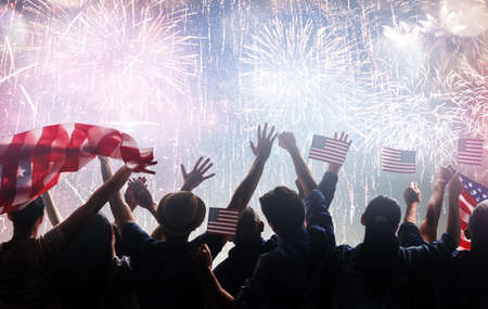 Patriotic holiday. Silhouettes of people holding the Flag of the USA. America celebrate 4th of July.