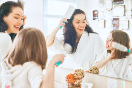Happy family! Mother and daughter child girl are combing hair in the bathroom.の写真素材