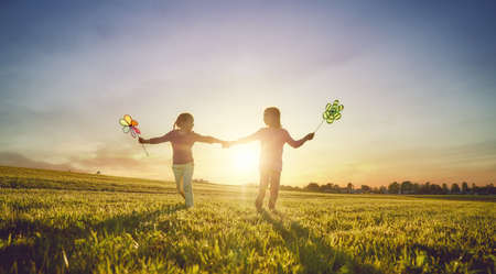Happy kids is having fun on nature in the summer. Children are laughing and playing on meadow at sunset background.の写真素材