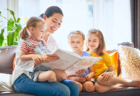 happy loving family. pretty young mother reading a book to her daughtersの写真素材