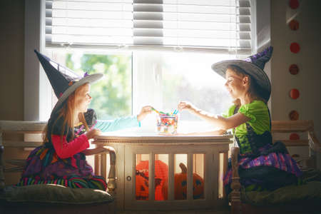 Cute little children girls with carving pumpkin. Happy family preparing for Halloween. Funny kids at home.の写真素材
