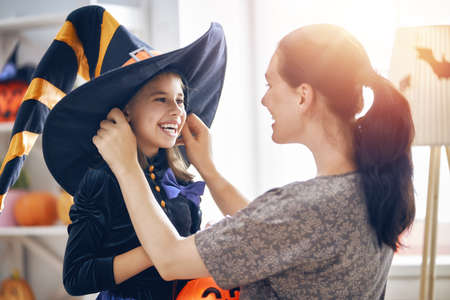 Happy family preparing for Halloween! Young mom and her kid in carnival costumes celebrate the...