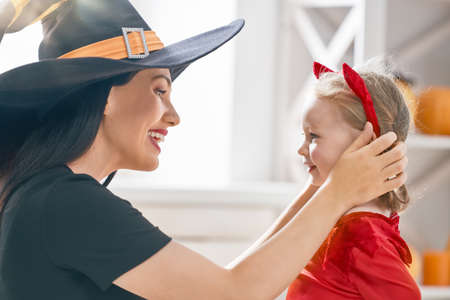 Happy family preparing for Halloween! Young mom and her kid in carnival costumes celebrate the...