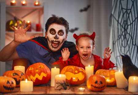 Father and his kid having fun at home. Happy family celebrating Halloween. People wearing carnival costumes and makeup.の写真素材