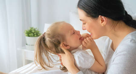 A nice baby girl and her mother enjoy sunny morning. Good time at home.