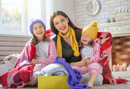 Winter portrait of happy loving family wearing knitted sweaters. Mother and children girls having fun, playing and laughing at home. Fashion concept.の写真素材
