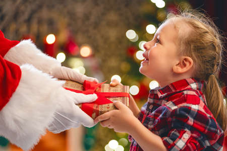 Hands of Santa Claus giving a x-mas gift to child.の写真素材
