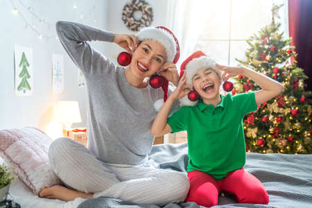 Merry Christmas and Happy Holidays! Mom and daughter having fun on bed. The morning before Xmas....