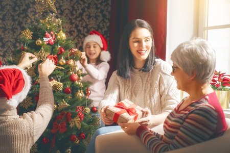 Merry Christmas and Happy Holidays! Grandma, mum, dad and child exchanging gifts. Parents and...