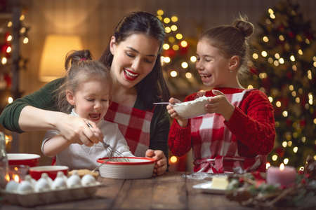 Merry Christmas and Happy Holidays. Family preparation holiday food. Mother and daughter cooking cookies.の写真素材