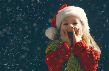 Merry Christmas and happy holidays! Little girl with snow. Child enjoying the game outdoors. Portrait kid on dark background.の写真素材