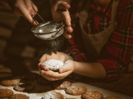 Close up view of bakers are working. Homemade family cookies. Hands of mother and daughter preparing biscuits on wooden table.の写真素材