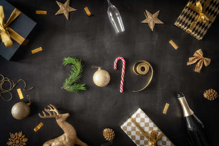 Happy New Year! Baubles, gift boxes and bottle of sparkling wine on black desk. Top view. Holiday...