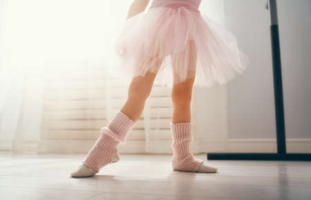 Cute little girl dreams of becoming a ballerina. Child girl in a pink tutu dancing in a room. Baby girl is studying ballet.の写真素材