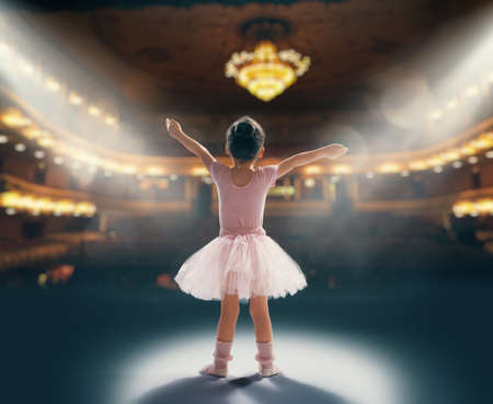 Cute little girl dreaming of becoming a ballerina. Child girl in a pink tutu dancing on the stage....
