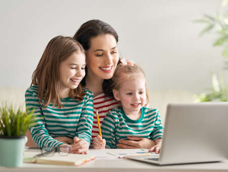 Young mother with children working on the computer from home. Happy family enjoying success.の写真素材