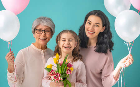 Happy women's day! Child daughter is congratulating mom and grandma giving them yellow flowers...