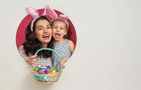 Happy holiday! Mother and her daughter with painting eggs. Family preparing for Easter. Cute little...