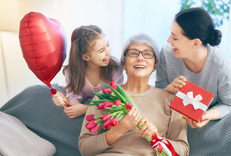 Happy women's day! Child daughter is congratulating mom and granny giving them flowers tulips....