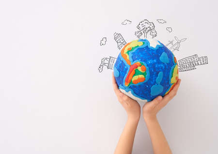 Child holding planet in hands against white background. Earth day holiday concept.の写真素材