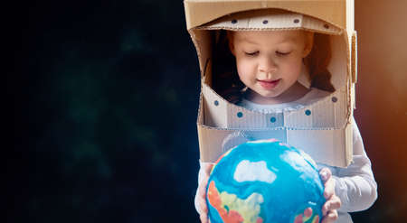 Child is dressed in an astronaut costume. Kid with globe. Earth day.の写真素材