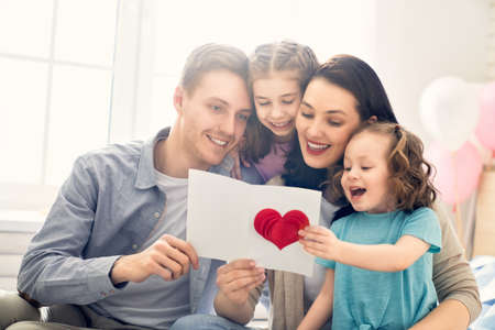 Happy mother's day! Children daughters with dad congratulating mom and give her flowers, gift and...