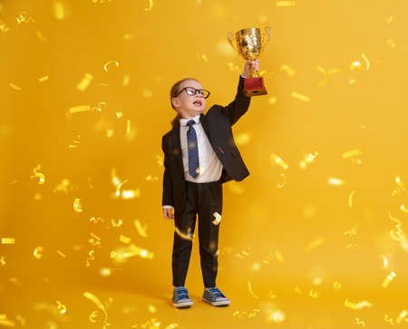 Little child is winner. Kid on the background of bright yellow wall. Smart power concept. Golden...