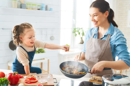 Healthy food at home. Happy family in the kitchen. Mother and child daughter are preparing proper meal.の写真素材