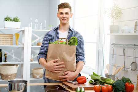 Healthy food at home. Happy man is preparing the proper meal in the kitchen.の写真素材