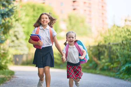 Pupils of primary school. Girls with backpacks outdoors. Beginning of lessons. First day of fall.の写真素材