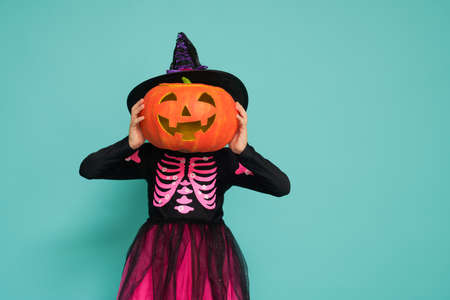 Happy Halloween! Cute little witch with a pumpkin on turquoise background.の写真素材