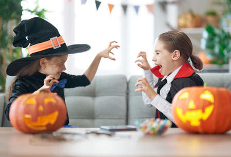 Cute little children girls with carving pumpkin. Happy family preparing for Halloween. Funny kids at home.の写真素材