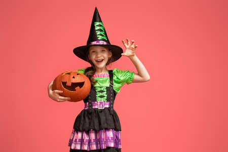 Happy Halloween! Cute little witch with a pumpkin on pinkの写真素材