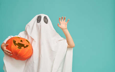 Happy Halloween! Cute little kid in ghost costume on tealの写真素材