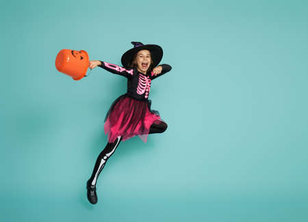 Happy Halloween! Cute little witch with a basket on turquoiseの写真素材