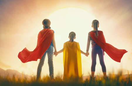 Little children are playing superhero. Kids on the background of sunset sky. Girl power conceptの写真素材