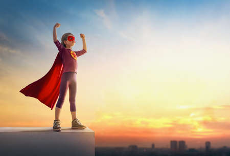 Little child playing superhero. Kid on the background of sunset sky. Girl power conceptの写真素材