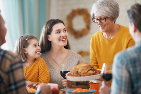 Happy Thanksgiving Day! Autumn feast. Family sitting at the table and celebrating holiday. Grandparents, mother, father and child. Traditional dinner.の写真素材