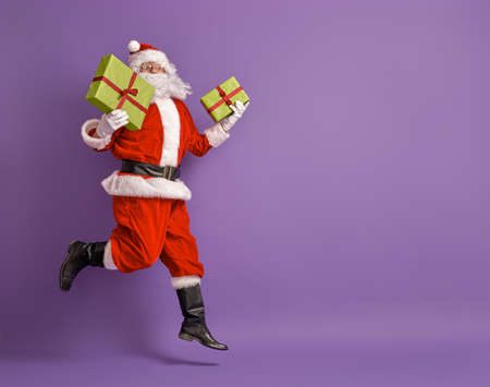 Merry Christmas and Happy Holidays! Santa Claus with present on bright color background.の写真素材