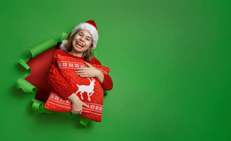 Merry Christmas! Little girl in Santa's hat on bright color background. Red and green.の写真素材