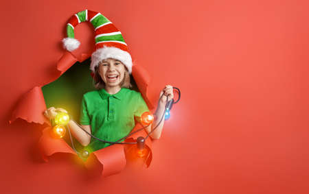 Merry Christmas! Little girl in Santa's elf costume on bright color background. Red and green.