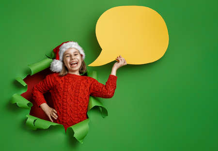 Merry Christmas! Little girl in Santa's hat on bright color background. Red and green.