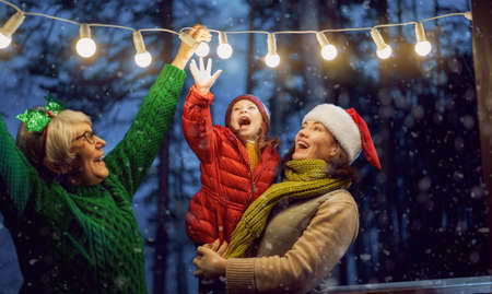 Merry Christmas and Happy Holidays! Cheerful mom, granny and cute girl decorating home. Parents and...