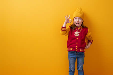 Portrait of a cute little girl in fashionable clothes. Hip-hop style. Kid on bright color background.の写真素材