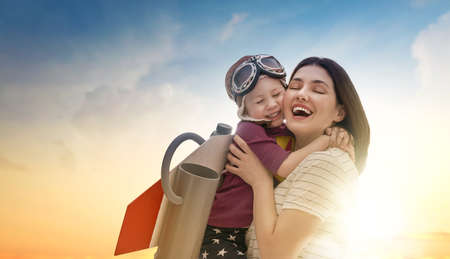 Mother and her child playing together. Girl in an astronaut costume dreaming of becoming a spaceman....