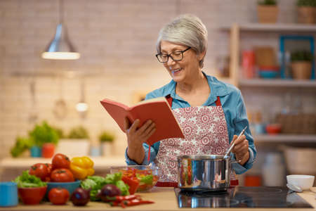 Healthy food at home. Happy woman is preparing vegetables and fruit in the kitchen.の写真素材