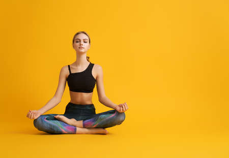 Woman is practicing yoga and meditation on color background.の写真素材