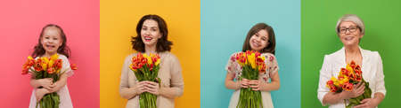 Happy women's day! Children, young mom and grandma with flowers tulips.Granny, mum and girls smiling on colorful background. Family holiday and togetherness. Three generationsの写真素材