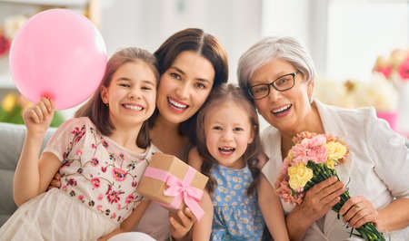 Happy women's day! Children daughters are congratulating mom and granny giving them flowers and...