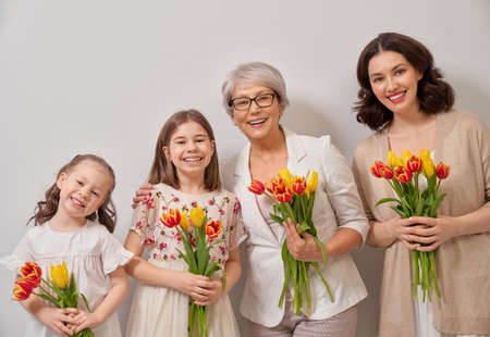 Happy women's day! Children daughters are congratulating mom and grandma giving them flowers...